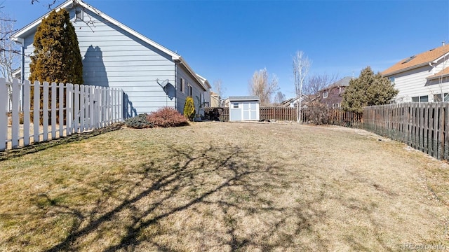 view of yard with an outbuilding, a fenced backyard, and a shed