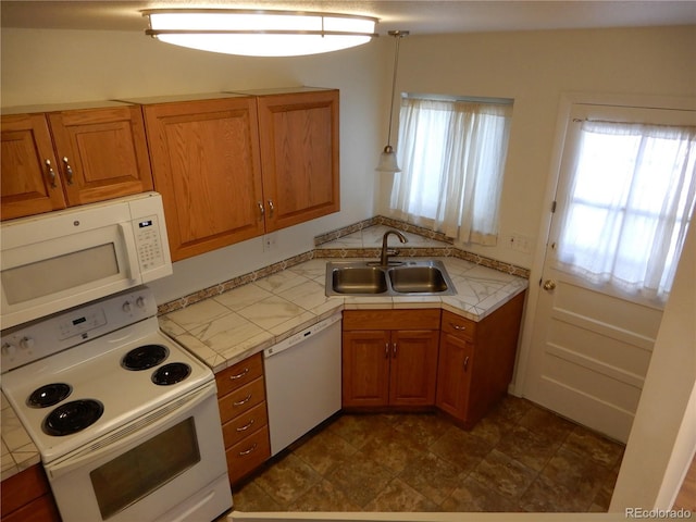 kitchen with hanging light fixtures, sink, tile countertops, and white appliances