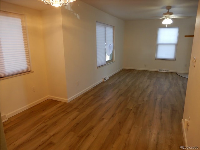 spare room with ceiling fan with notable chandelier and dark hardwood / wood-style flooring