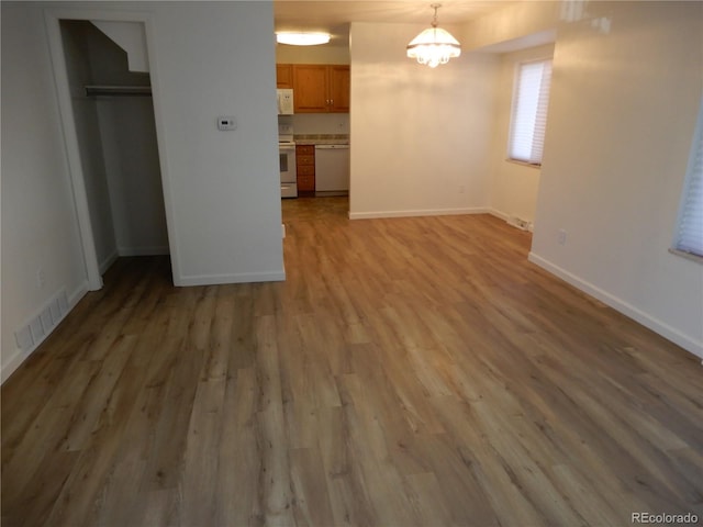 unfurnished dining area with an inviting chandelier and hardwood / wood-style floors