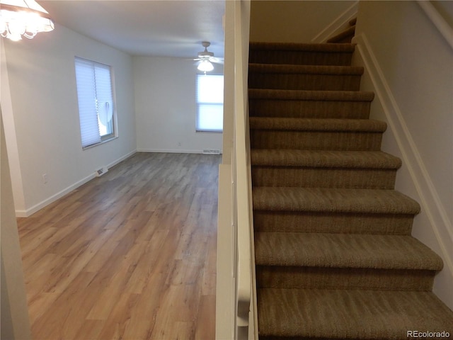 stairway with hardwood / wood-style floors and ceiling fan