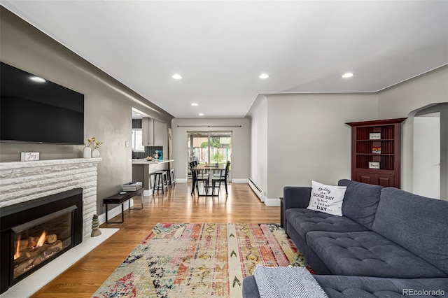 2845 Hudson St, Denver, CO 80207 - living area featuring a baseboard heating unit, recessed lighting, light wood-style floors, and a warm lit fireplace