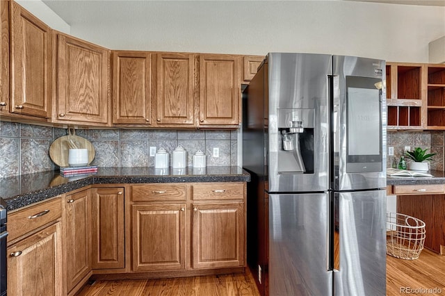 kitchen with decorative backsplash, stainless steel fridge, light wood-style flooring, and brown cabinets