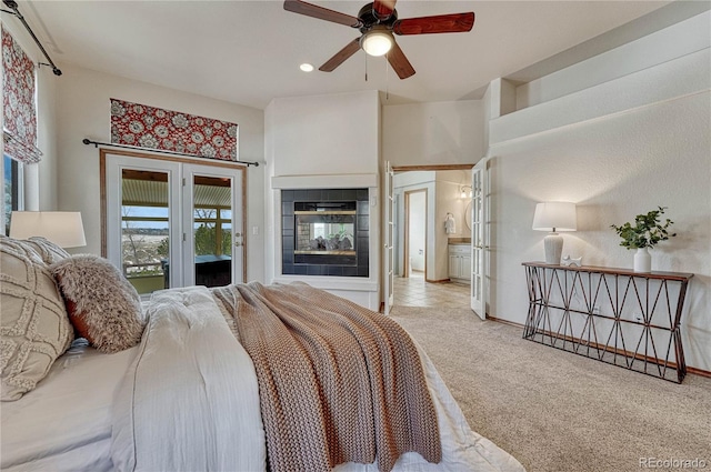 carpeted bedroom with access to exterior, a ceiling fan, and a tiled fireplace