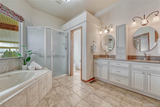 bathroom featuring a garden tub, double vanity, a shower stall, and a sink