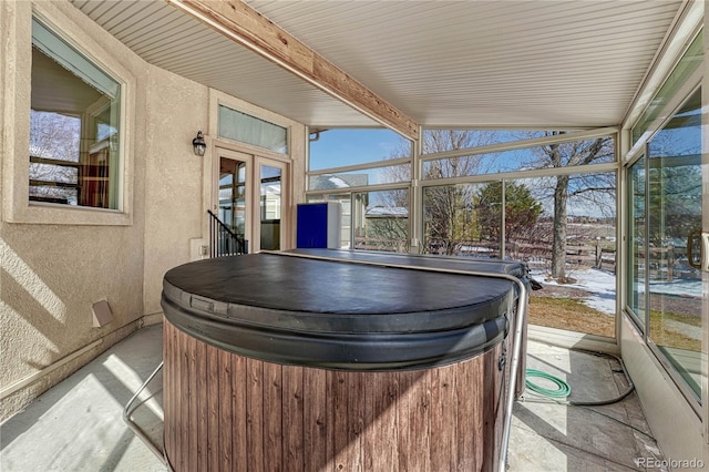 sunroom / solarium featuring plenty of natural light, beamed ceiling, and french doors