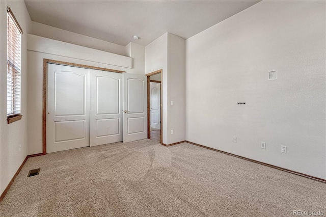 unfurnished bedroom with carpet flooring, baseboards, visible vents, and a closet