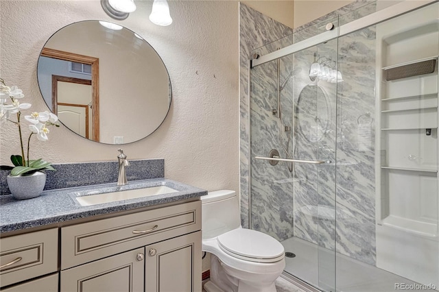 bathroom with vanity, a shower stall, toilet, and a textured wall