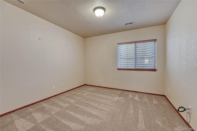 empty room with visible vents, baseboards, carpet, a textured wall, and a textured ceiling