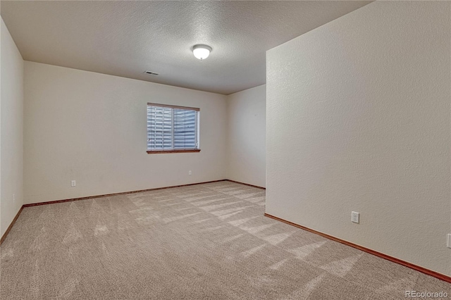 empty room featuring visible vents, baseboards, light carpet, a textured wall, and a textured ceiling