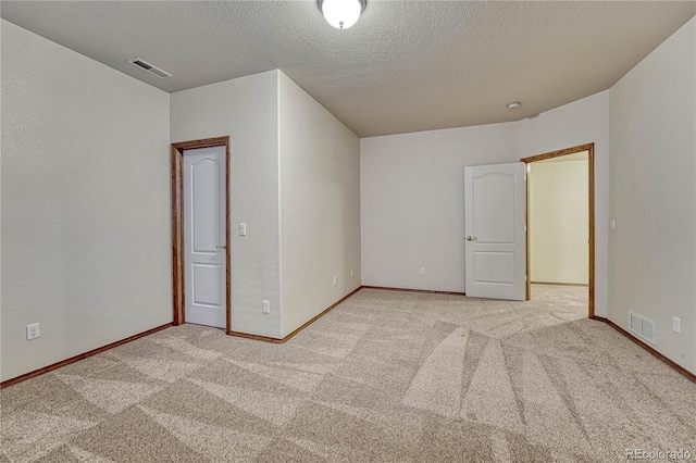 empty room featuring visible vents, light carpet, and a textured ceiling