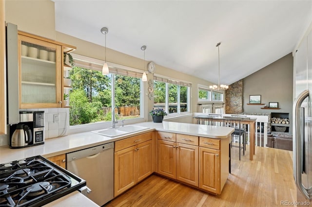6083 S Glencoe Way, Centennial, CO 80121 - kitchen with appliances with stainless steel finishes, a sink, light wood finished floors, a chandelier, and a peninsula