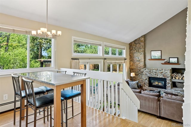 6083 S Glencoe Way, Centennial, CO 80121 - dining area featuring wood finished floors, a chandelier, healthy amount of natural light, a stone fireplace, and high vaulted ceiling