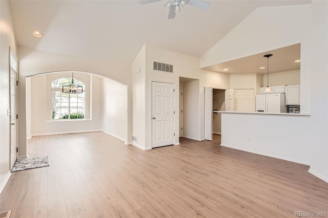 unfurnished living room with ceiling fan, high vaulted ceiling, arched walkways, light wood-style flooring, and baseboards