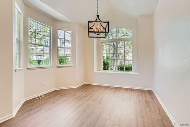 unfurnished dining area with a chandelier, light wood-style flooring, baseboards, and lofted ceiling
