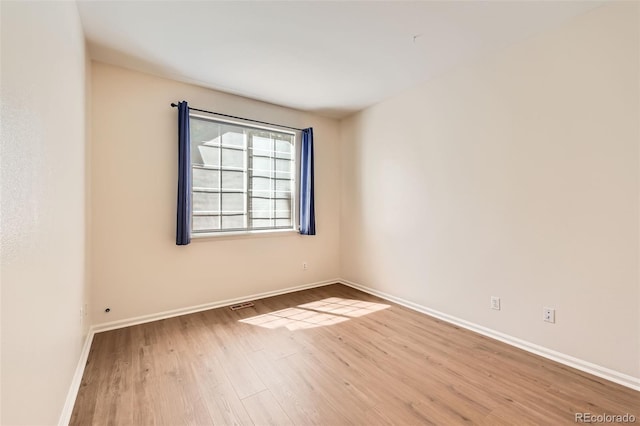 spare room featuring wood finished floors and baseboards