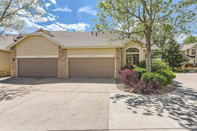 view of front of home with driveway, a garage, stone siding, and a shingled roof