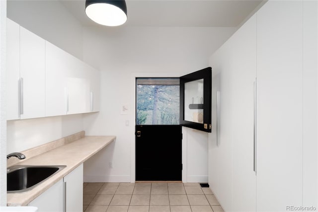 kitchen featuring sink, light tile patterned floors, and white cabinets