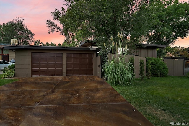 garage at dusk featuring a detached garage and a yard