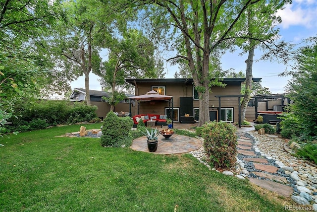 rear view of property featuring a patio area, an outdoor fire pit, and a yard