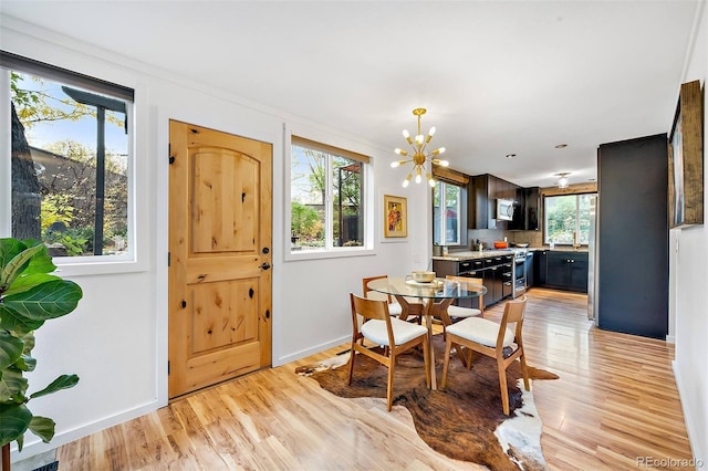 dining room with an inviting chandelier, light wood-style flooring, and baseboards