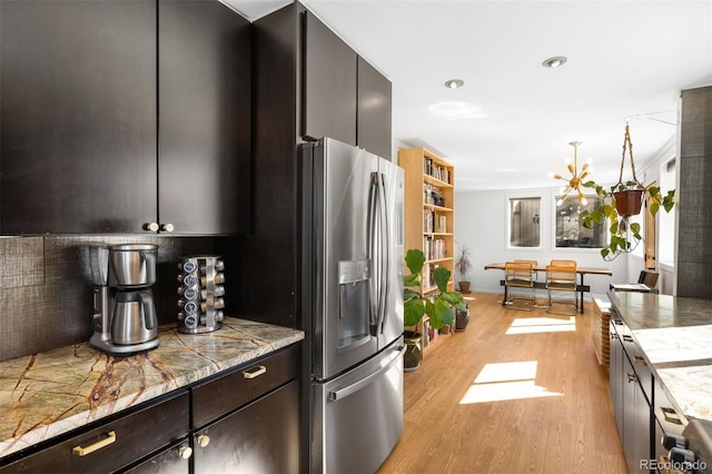 kitchen with decorative backsplash, light wood-style floors, dark brown cabinetry, a chandelier, and stainless steel fridge with ice dispenser