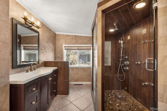 bathroom featuring vanity, a tile shower, tile walls, and tile patterned floors