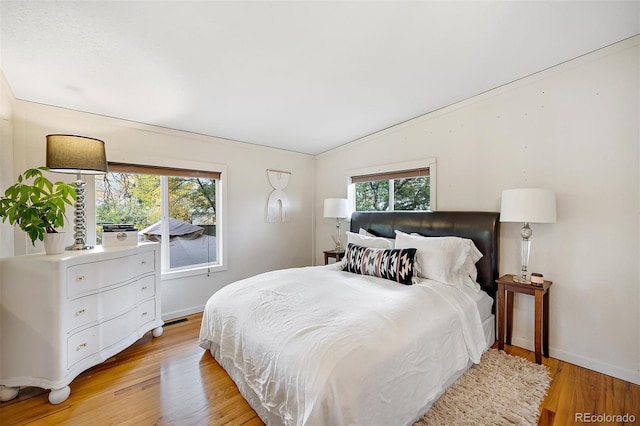 bedroom with lofted ceiling, light wood-style floors, visible vents, and baseboards