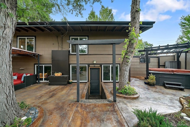 rear view of house featuring a patio area, a hot tub, and a pergola