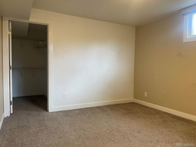 unfurnished bedroom with a spacious closet, a closet, and carpet flooring