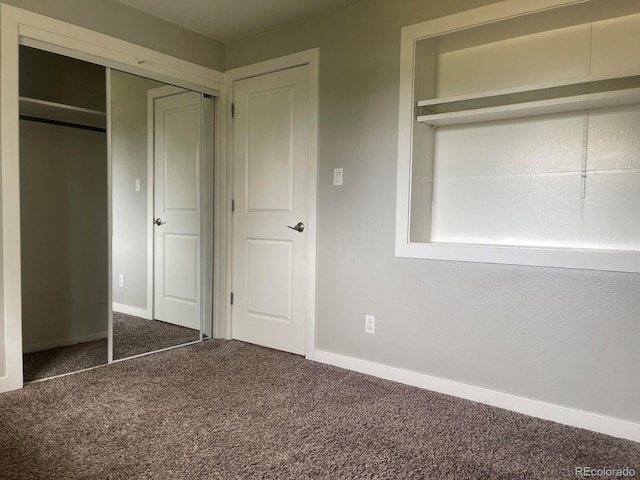 unfurnished bedroom with a closet and dark colored carpet