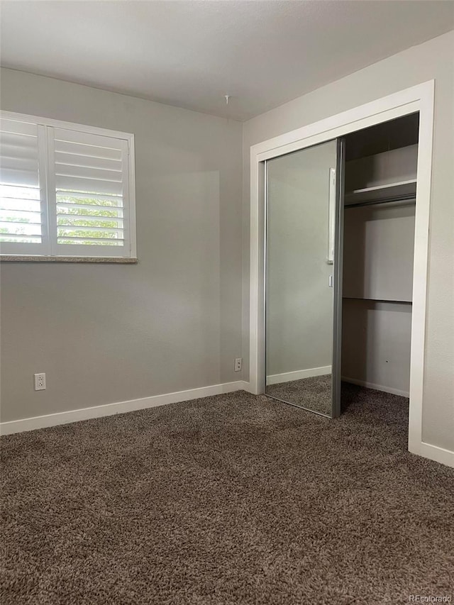 unfurnished bedroom featuring a closet and dark colored carpet