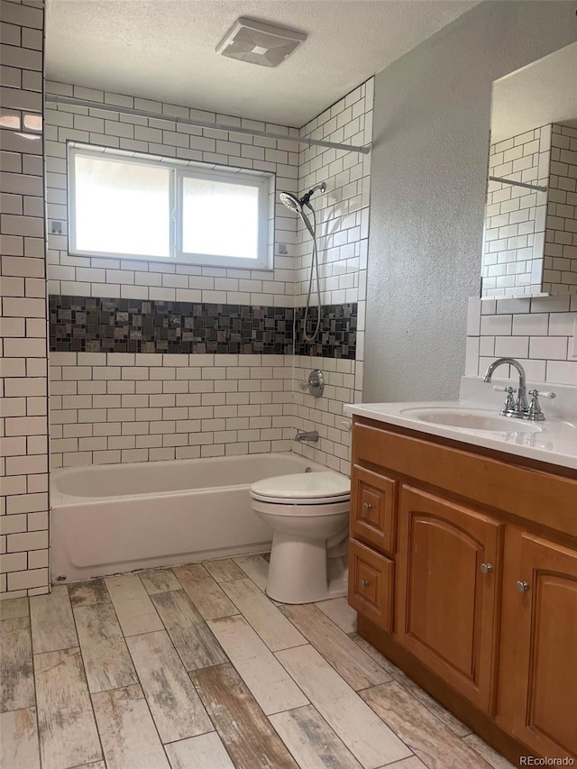 full bathroom with a textured ceiling, tiled shower / bath, vanity, decorative backsplash, and toilet