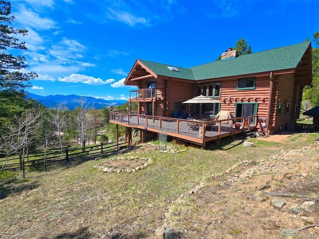 6241 Kilimanjaro Dr, Evergreen, CO 80439 - rear view of house featuring log siding, fence, a deck with mountain view, a chimney, and a lawn