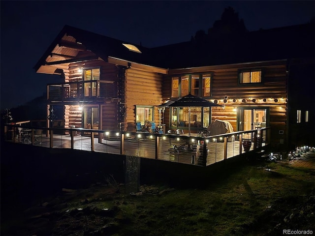 6241 Kilimanjaro Dr, Evergreen, CO 80439 - back of house at night featuring a balcony and log siding
