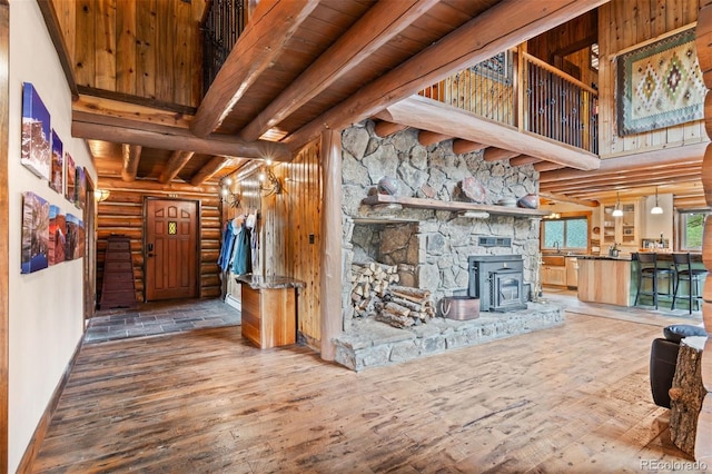 6241 Kilimanjaro Dr, Evergreen, CO 80439 - unfurnished living room featuring log walls, hardwood / wood-style floors, beam ceiling, a wood stove, and baseboards