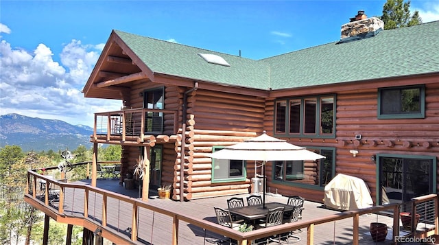6241 Kilimanjaro Dr, Evergreen, CO 80439 - rear view of house featuring log siding, outdoor dining area, a deck with mountain view, and a chimney