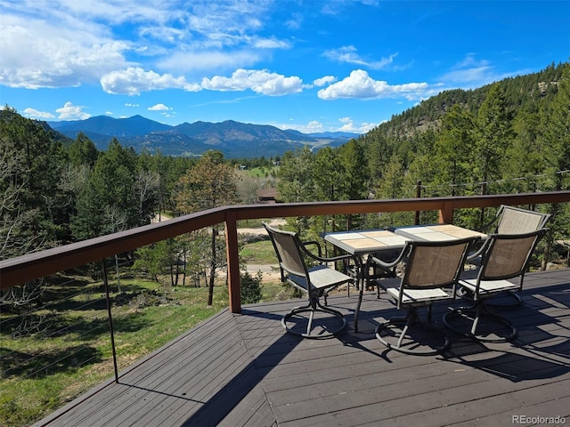 6241 Kilimanjaro Dr, Evergreen, CO 80439 - deck with a forest view, outdoor dining space, and a mountain view