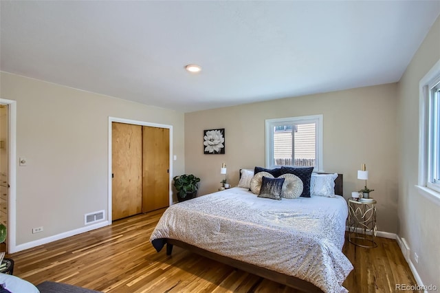 bedroom featuring a closet, visible vents, wood finished floors, and baseboards
