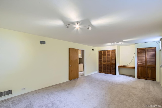carpeted empty room featuring visible vents and track lighting
