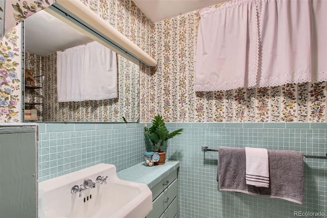 bathroom featuring a sink, wallpapered walls, and a wainscoted wall
