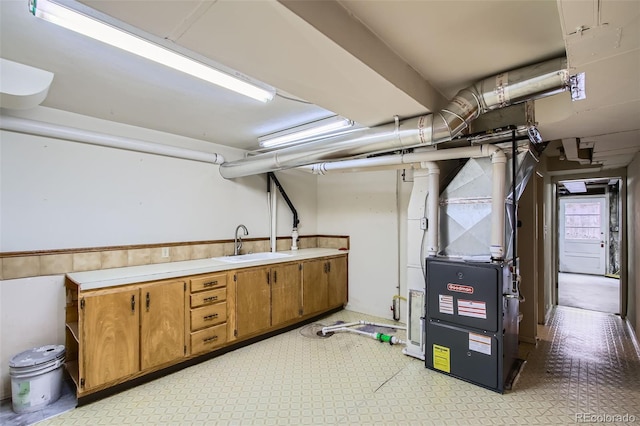 finished below grade area with light floors, heating unit, and a sink