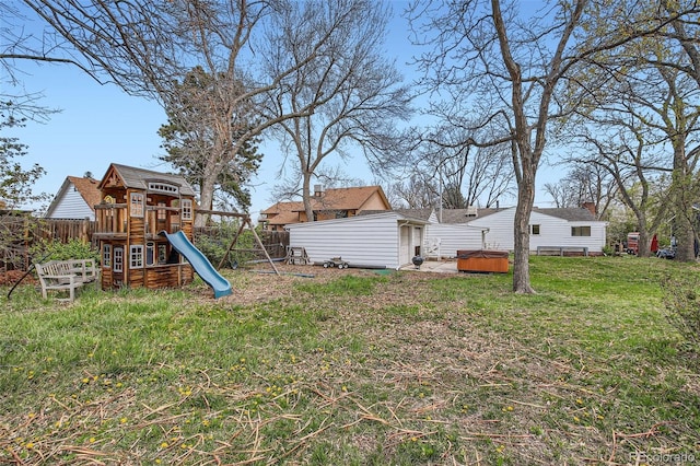 view of yard featuring a playground, a hot tub, and fence private yard