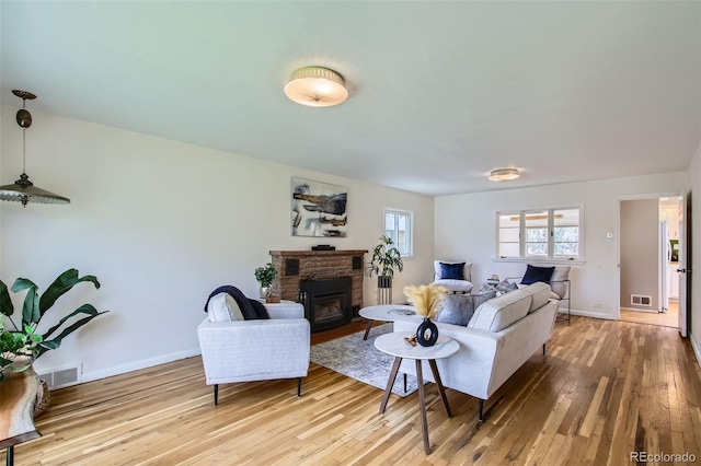 living room with wood-type flooring, baseboards, visible vents, and a glass covered fireplace