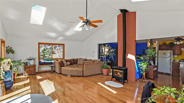 1269 Roland Dr, Bailey, CO 80421 - living room featuring a wood stove, a skylight, high vaulted ceiling, ceiling fan, and light wood-type flooring