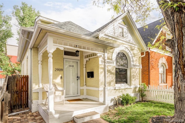 2909 Glenarm Pl, Denver, CO 80205 - view of front of property featuring a shingled roof, fence, covered porch, and brick siding