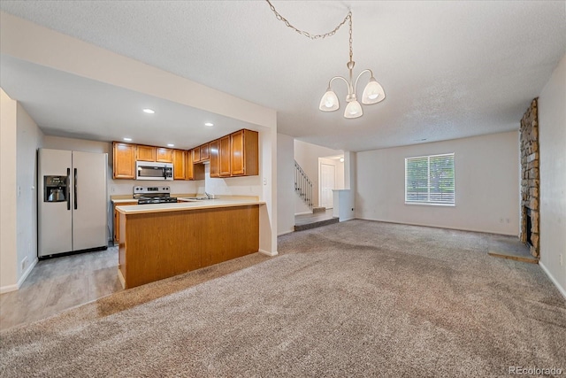 8438 Everett Way Unit B, Arvada, CO 80005 - kitchen with stainless steel appliances, open floor plan, brown cabinets, a chandelier, and light carpet