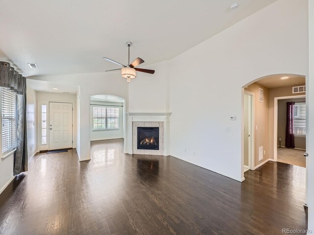 unfurnished living room featuring ceiling fan, a tile fireplace, and dark hardwood / wood-style floors