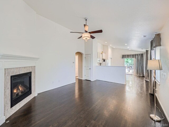 unfurnished living room featuring lofted ceiling, a tiled fireplace, ceiling fan, and dark wood-type flooring