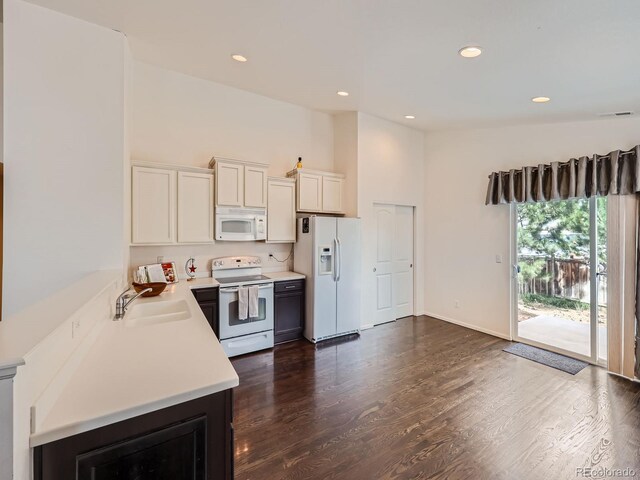 kitchen featuring white cabinets, lofted ceiling, sink, white appliances, and dark hardwood / wood-style floors